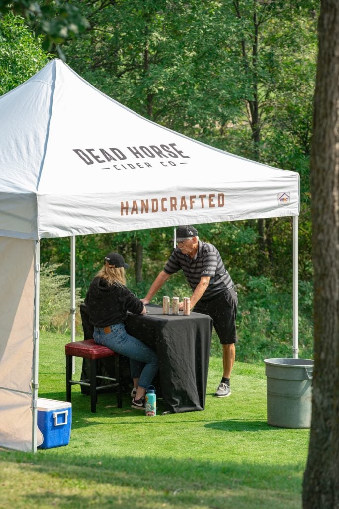 golfer stops to visit the Dead Horse Cider Co tent