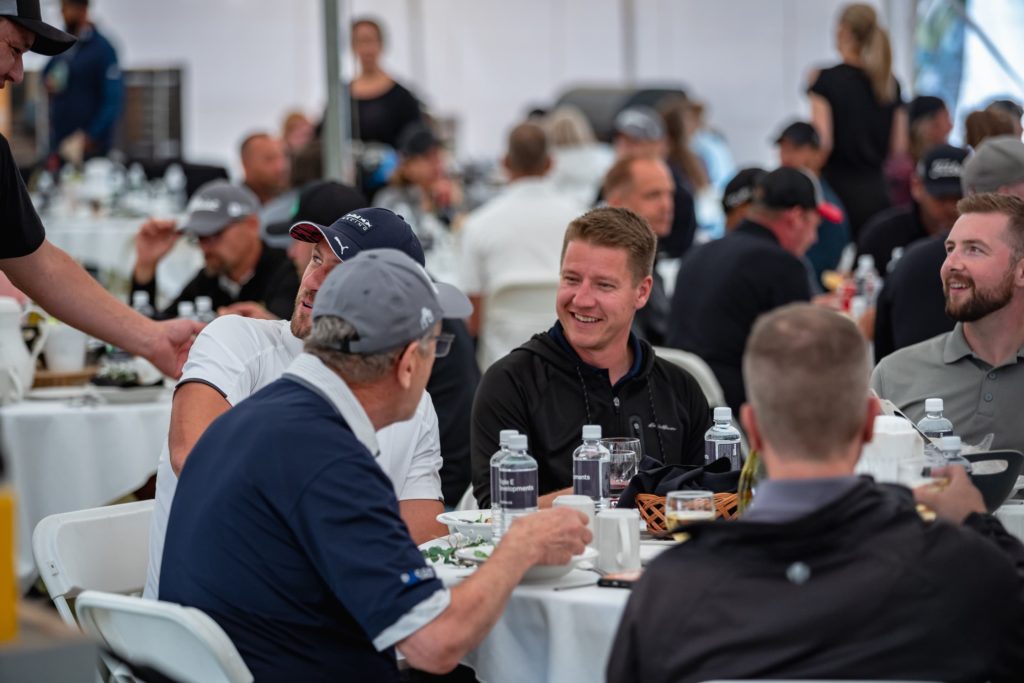 Golfers smiling as they enjoy dinner around a table